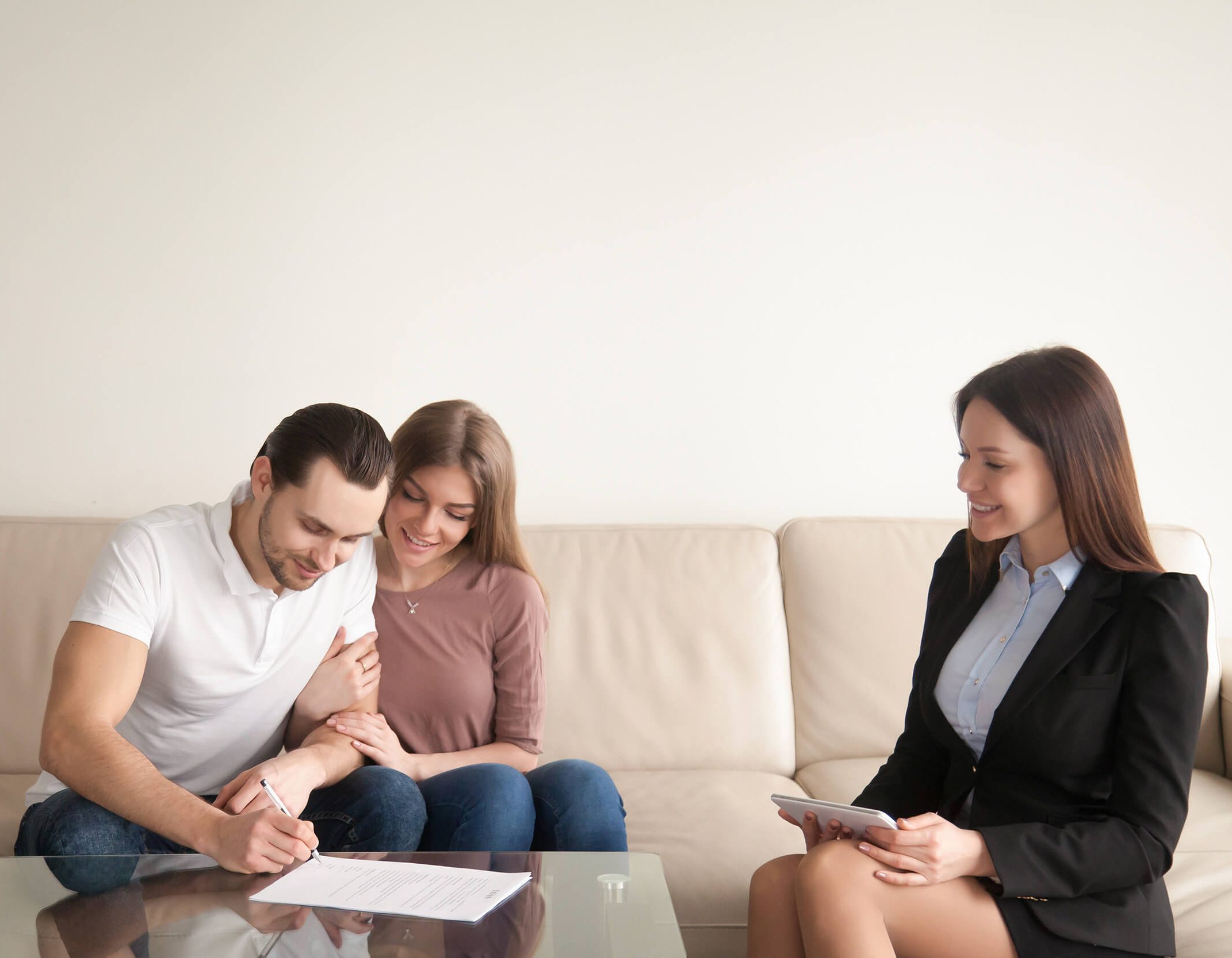 young man signing papers sitting wife realtor
